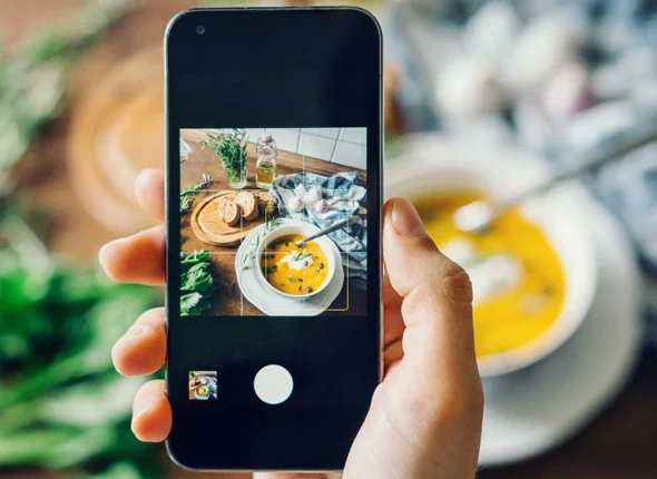 person photographing food with their smartphone and using a grid